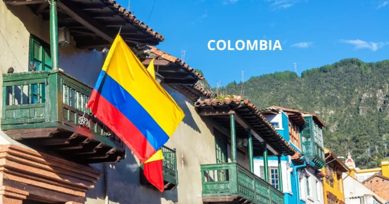 Colombian flag hanging from a colourful colonial balcony in Bogotá’s historic district with mountains in the background.