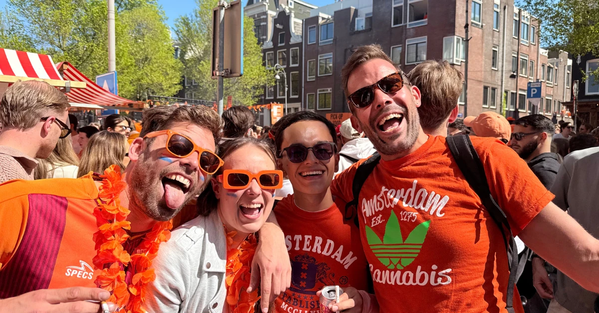 Lars and Sebas celebrating Kings Day 2025 in Amsterdam with Flora and Thomas, wearing orange and enjoying the festive atmosphere.