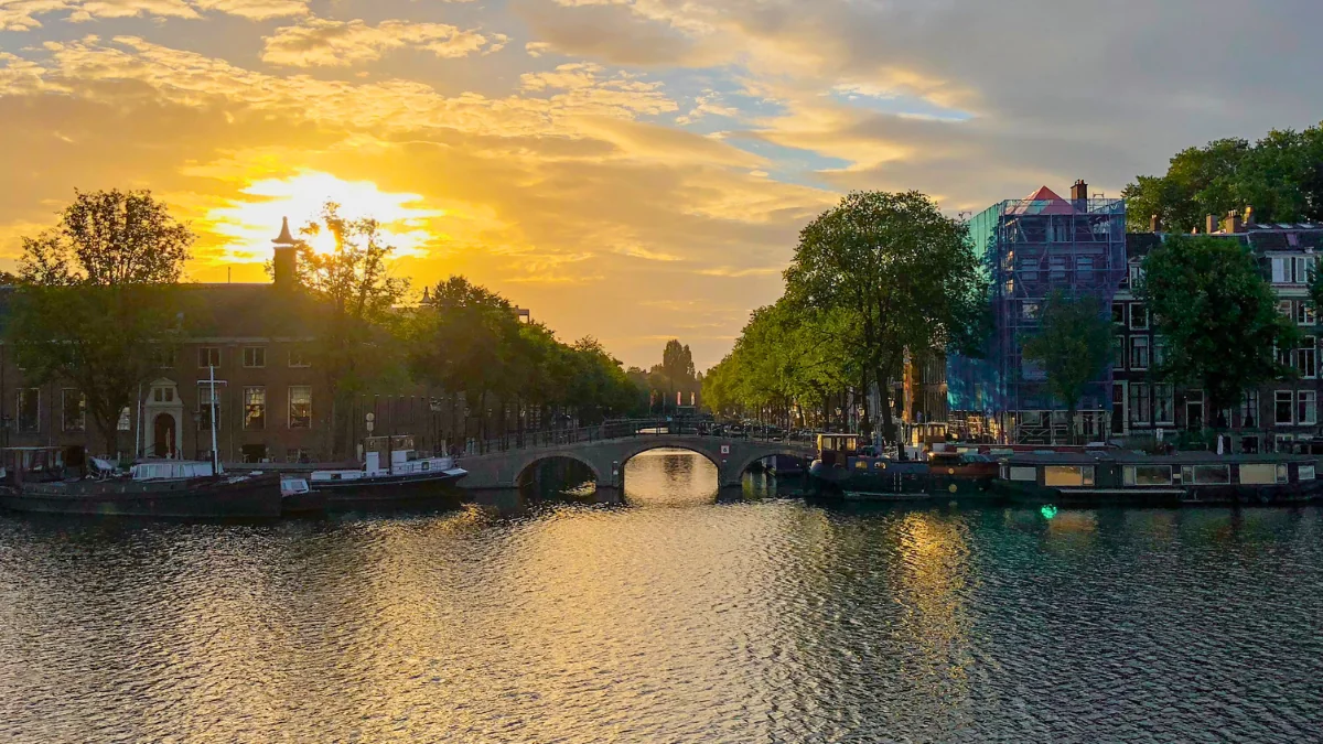 Golden sunset over the Amsterdam canals reflecting on the water, symbolising endings, freedom, and the beauty of letting go.